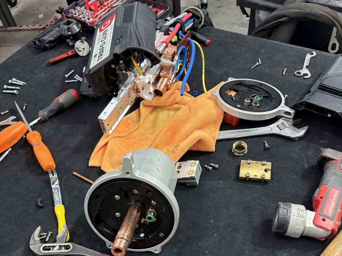 Disassembled spot-welding gun and hand tools on a shop table